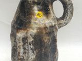un vase marron et noir sur lequel est apposée une étiquette jaune