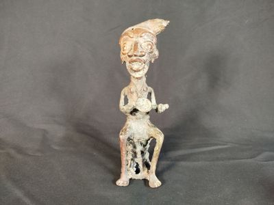 statue représentant une femme assise sur un tabouret, avec un oiseau sur l'épaule