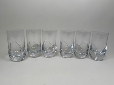 six verres à pied en verre transparent alignés sur une surface blanche