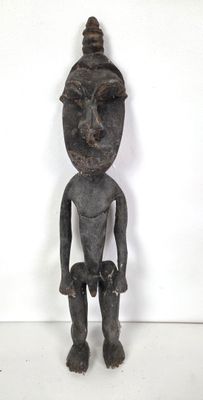 une vieille statue en bois d'un homme avec un chapeau sur la tête