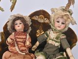 two dolls sitting next to each other on a chair