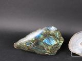 two pieces of labradorite and a rock on a black surface