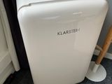 a small white refrigerator sitting next to a window