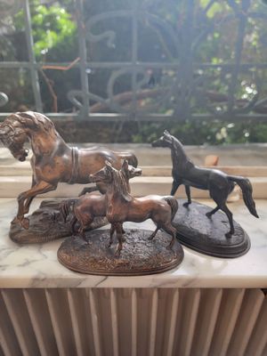 three bronze statues of horses on a marble table