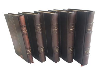 six vieux livres alignés sur une surface blanche