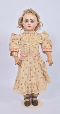 an old doll with blonde hair and a dress on a white surface