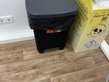 une poubelle noire posée à côté d'une autre poubelle noire