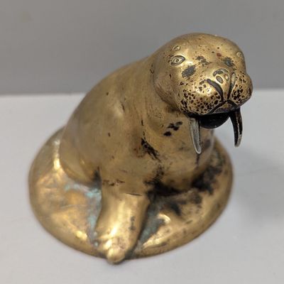 une statuette en forme de sceau doré posée sur une table blanche