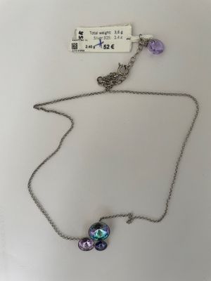 a close up of a necklace on a white surface with a tag