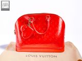 a red louis vuitton bag sitting on top of a pillow