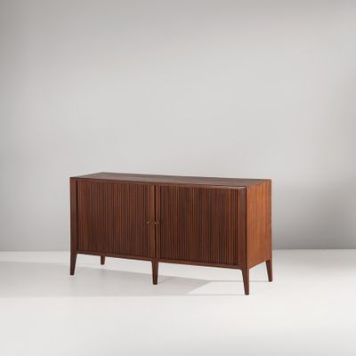 Le buffet est en bois et comporte deux portes et deux tiroirs.