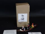 un petit bateau miniature avec des personnages à bord, à côté d'une boîte