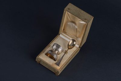a silver spoon and spoon in a box on a black surface