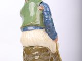 a figurine of a man sitting on a tree stump