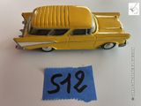 une petite voiture jaune posée à côté d'une feuille de papier bleue