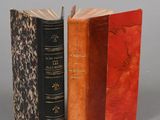 two old books sitting next to each other on a gray surface