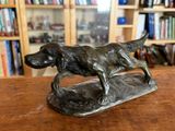 statue d'un chien en train de courir sur une table en bois devant une bibliothèque