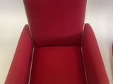 pair of red chairs with white piping on the arms and legs