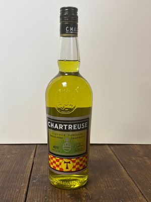 La bouteille de Chartreuse est posée sur une table en bois.