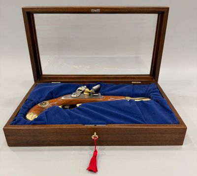 une boîte en bois contenant un pistolet, posée sur un tissu bleu