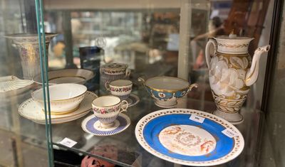 une vitrine en verre contenant de nombreux modèles de tasses à thé et de soucoupes