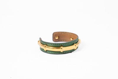 un gros plan d'un bracelet en cuir vert sur fond blanc