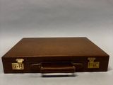 valise en cuir marron avec des poignées en laiton sur fond blanc