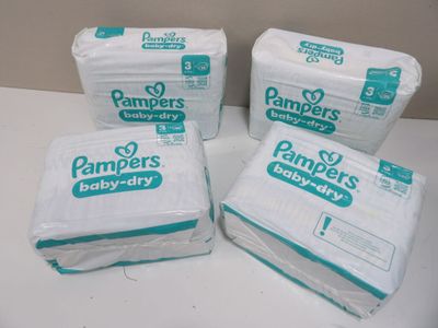 quatre paquets de couches Pampers Baby Dry posés sur une table