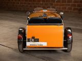 a small orange car parked in front of a brick wall