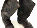 une paire de bottes en cuir noir posée sur une surface blanche