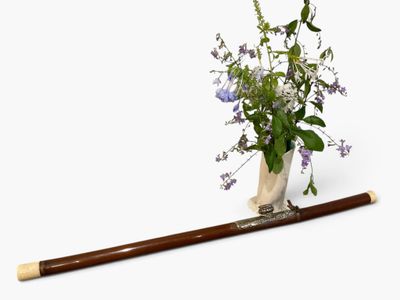 a vase with flowers and a baseball bat on a white surface
