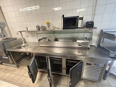 une cuisine équipée de plans de travail en inox et d'un micro-ondes