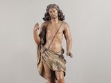 une vieille statue représentant un homme barbu tenant un sac