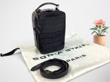 le petit sac noir est posé à côté d'une petite fleur rose