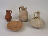 three clay vases and a plate on a white surface