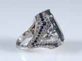 a close up of a diamond and sapphire ring on a white surface