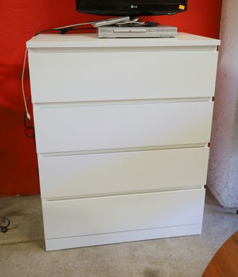 une télévision posée sur une commode blanche dans une pièce