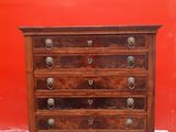a wooden chest of drawers against a red wall