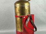 an old fire extinguisor with a red case and brass fittings