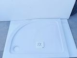 a close up of a white shower tray sitting on the ground