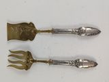 une paire d'ustensiles de table anciens en argent posés sur une surface blanche