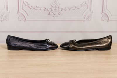 two pairs of black shoes sitting on top of a wooden floor
