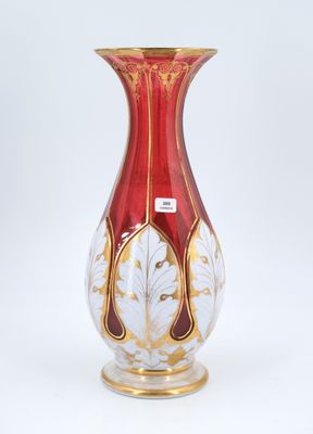 a red and gold vase sitting on a white surface