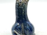 un vase bleu orné d'un chat, posé sur une table
