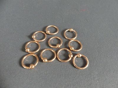 six gold filled open jump rings on a gray surface