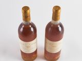 two bottles of wine sitting next to each other on a white surface
