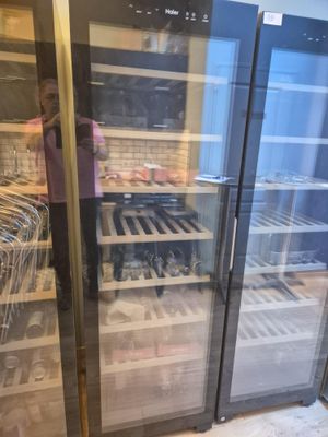 une femme debout devant un réfrigérateur à vin