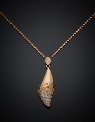un pendentif en or et diamants suspendu à une chaîne, sur fond noir
