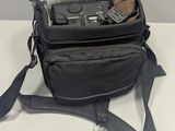 a black camera bag with a camera in it on a white table