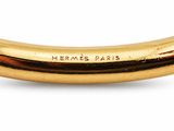 un gros plan sur un bracelet rigide en or portant l'inscription « Hermès Paris »